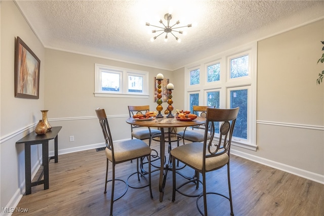 dining area with dark hardwood / wood-style floors, a textured ceiling, and a chandelier