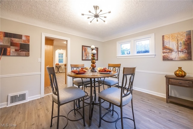 dining space with a chandelier, hardwood / wood-style floors, and a textured ceiling