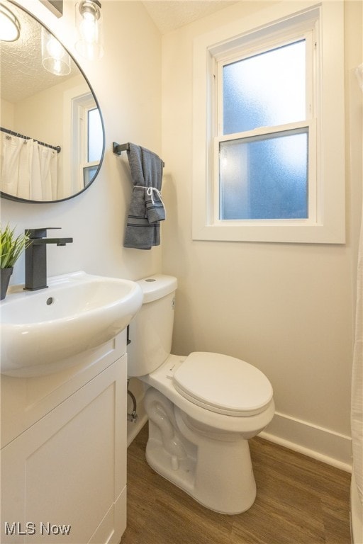 bathroom featuring toilet, vanity, wood-type flooring, and a textured ceiling