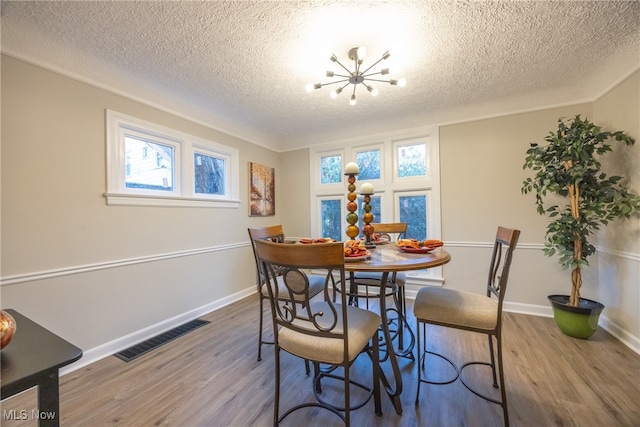 dining area with hardwood / wood-style floors, a notable chandelier, and a textured ceiling