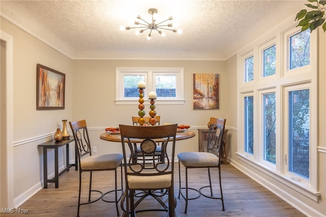 dining area with dark hardwood / wood-style flooring, an inviting chandelier, and a textured ceiling