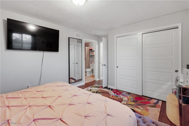 bedroom featuring ensuite bathroom, a textured ceiling, a closet, and hardwood / wood-style flooring