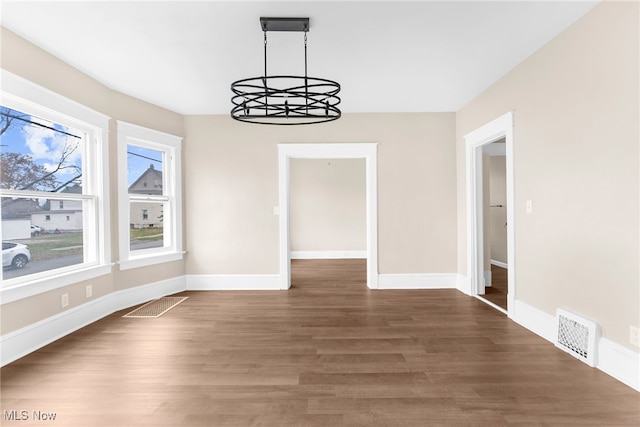 unfurnished dining area featuring a notable chandelier and dark hardwood / wood-style floors