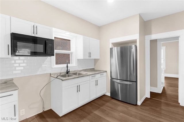 kitchen with white cabinetry, sink, dark wood-type flooring, stainless steel fridge, and decorative backsplash