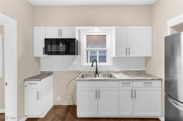 kitchen with stainless steel fridge, white cabinetry, and sink