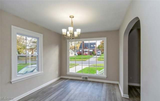 unfurnished dining area with dark hardwood / wood-style floors and a chandelier