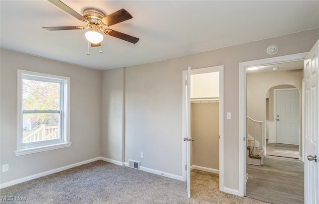 unfurnished bedroom featuring ceiling fan, a closet, a spacious closet, and light colored carpet