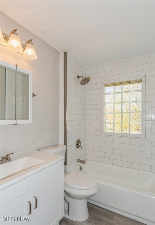 full bathroom featuring hardwood / wood-style floors, vanity, tiled shower / bath combo, and toilet