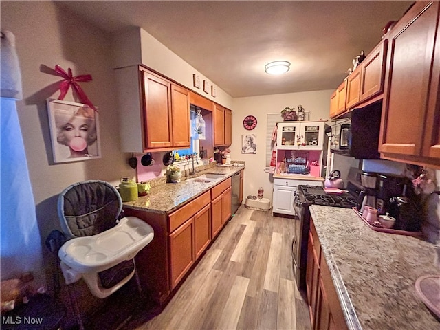 kitchen featuring black appliances, sink, light stone counters, and light hardwood / wood-style flooring