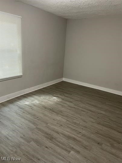 spare room featuring a textured ceiling and dark hardwood / wood-style floors