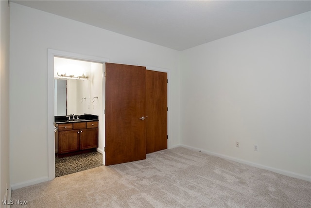 bedroom with connected bathroom, sink, and light colored carpet