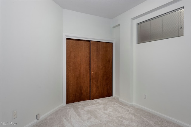 unfurnished bedroom with a closet and light carpet