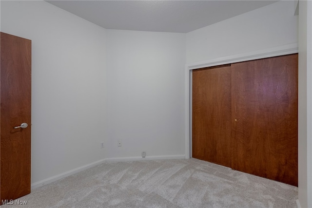 unfurnished bedroom with light carpet and a closet