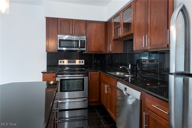 kitchen featuring appliances with stainless steel finishes, dark tile patterned floors, sink, and backsplash