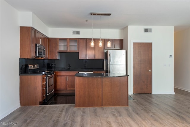 kitchen with stainless steel appliances, dark hardwood / wood-style floors, pendant lighting, and tasteful backsplash