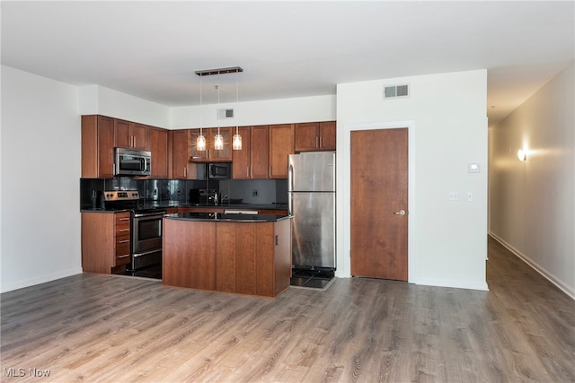 kitchen with stainless steel appliances, hardwood / wood-style floors, sink, backsplash, and decorative light fixtures