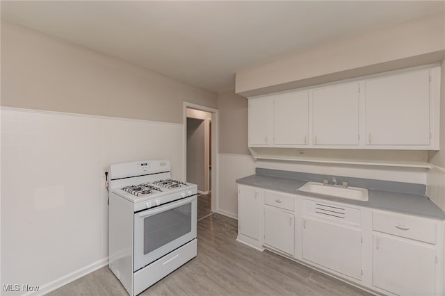 kitchen featuring white range with gas cooktop, light hardwood / wood-style floors, and white cabinets