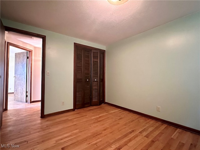 unfurnished bedroom with light hardwood / wood-style floors, a textured ceiling, and a closet