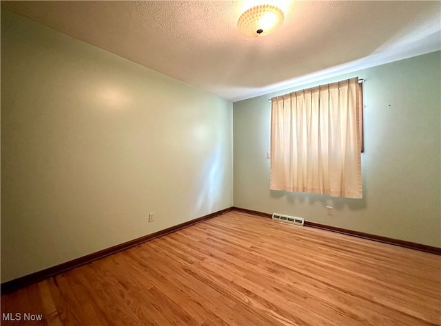 unfurnished room with hardwood / wood-style floors and a textured ceiling