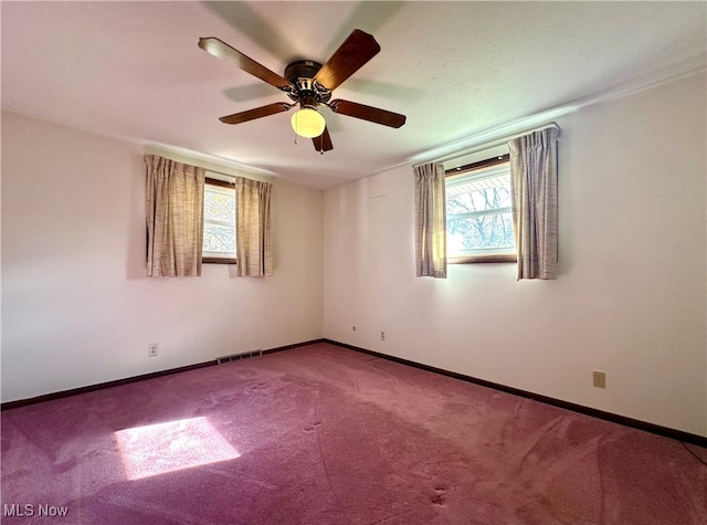 spare room featuring a wealth of natural light, carpet flooring, and ceiling fan