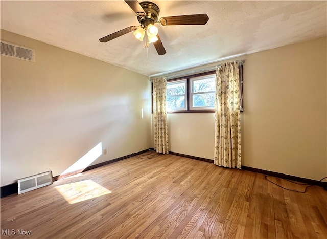 spare room with a textured ceiling, light wood-type flooring, and ceiling fan