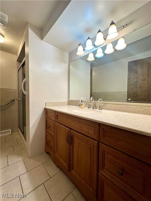 bathroom featuring vanity, walk in shower, tile patterned flooring, and a textured ceiling