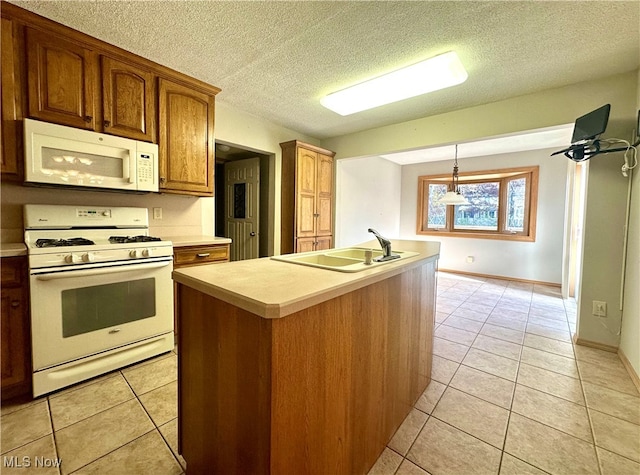 kitchen featuring light tile patterned flooring, a center island with sink, hanging light fixtures, sink, and white appliances