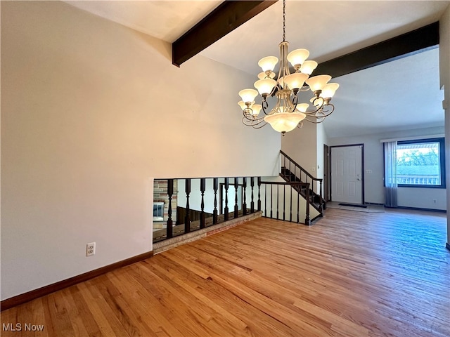 unfurnished living room with a chandelier, beam ceiling, and light hardwood / wood-style flooring