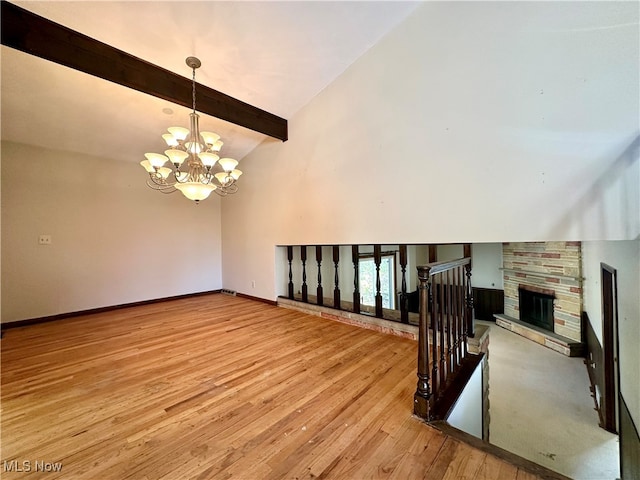 living room with lofted ceiling with beams, light wood-type flooring, an inviting chandelier, and a fireplace