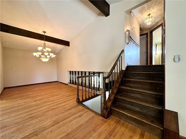 stairway with an inviting chandelier, wood-type flooring, and vaulted ceiling with beams