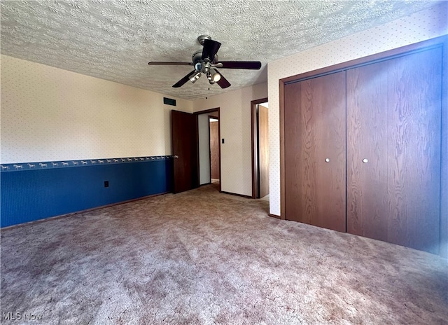 unfurnished bedroom with a closet, carpet, a textured ceiling, and ceiling fan