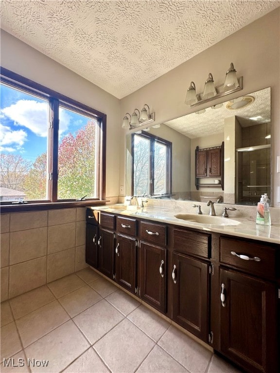 bathroom featuring vanity, a textured ceiling, tile patterned flooring, and a shower with door