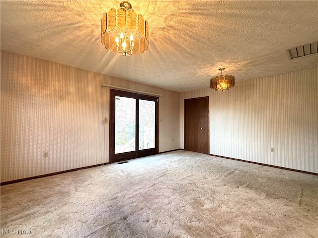 unfurnished room with a chandelier, a textured ceiling, and french doors