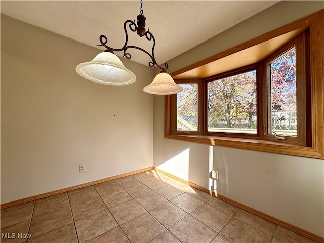 unfurnished dining area featuring a textured ceiling and light tile patterned floors