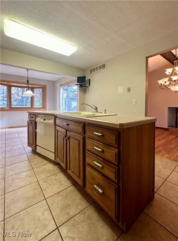 kitchen featuring light tile patterned flooring, sink, a textured ceiling, hanging light fixtures, and dishwasher