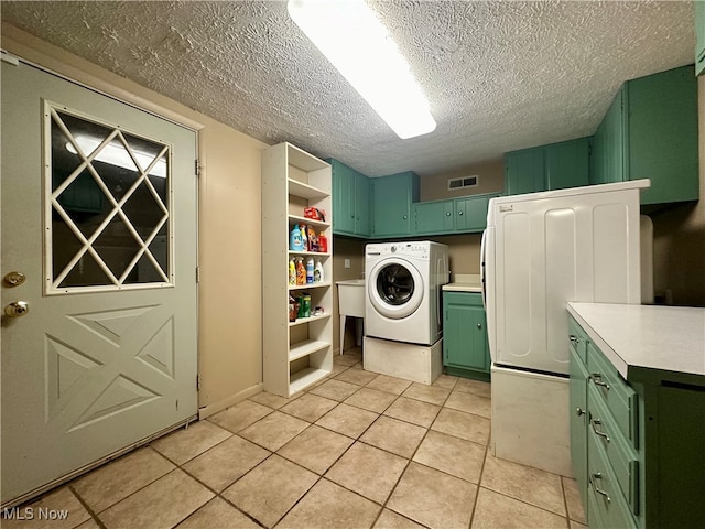 laundry area featuring washer / clothes dryer, cabinets, a textured ceiling, and light tile patterned floors