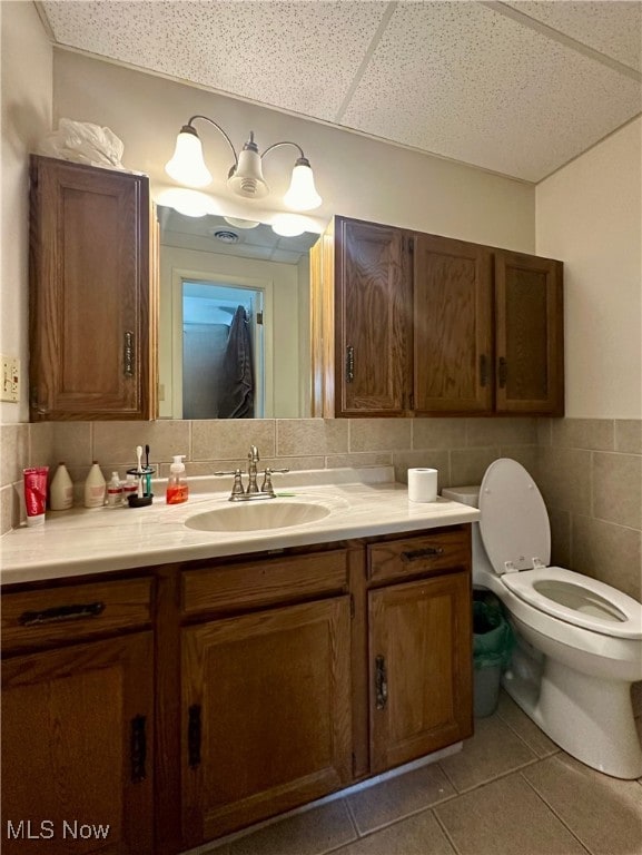 bathroom featuring vanity, tile patterned floors, toilet, and a drop ceiling