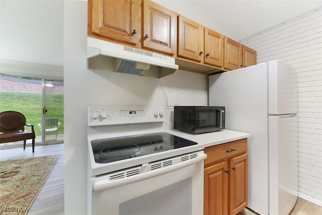 kitchen featuring white appliances, light hardwood / wood-style floors, and brick wall