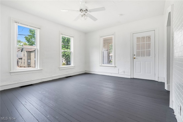 spare room featuring a wealth of natural light, dark wood-type flooring, and ceiling fan