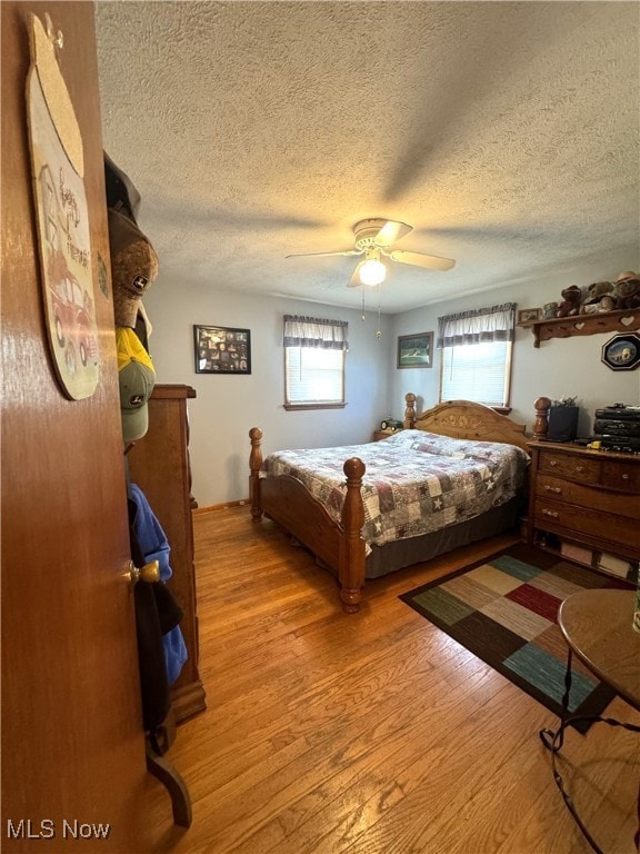 bedroom with ceiling fan, a textured ceiling, and light hardwood / wood-style floors