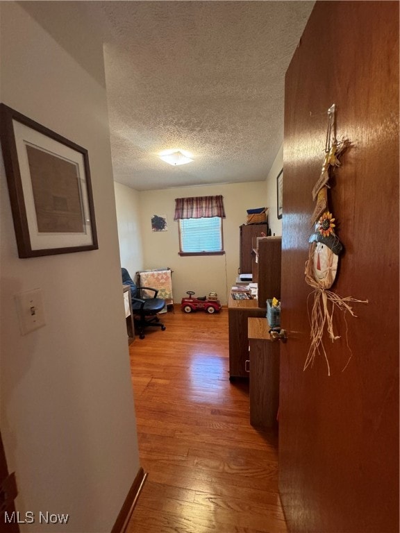 corridor with hardwood / wood-style floors and a textured ceiling