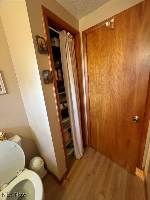 bathroom featuring hardwood / wood-style floors, a textured ceiling, and toilet