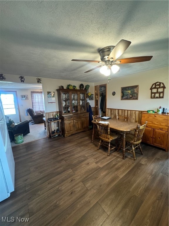 dining area featuring dark wood-type flooring, a textured ceiling, and ceiling fan