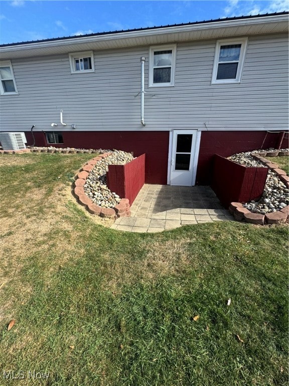 back of house featuring a lawn, cooling unit, and a patio area