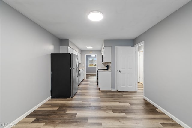 kitchen featuring white cabinets, hardwood / wood-style flooring, tasteful backsplash, and stainless steel fridge