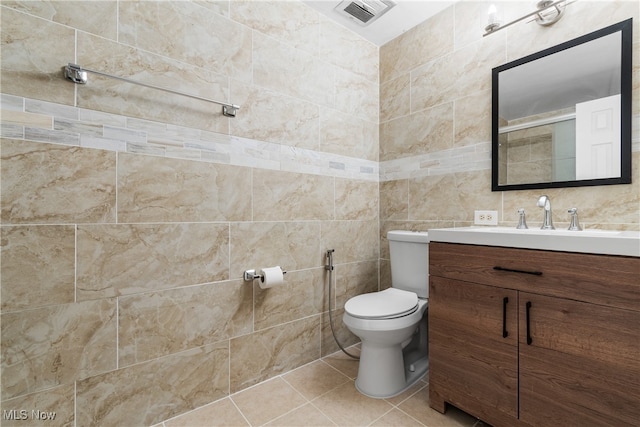 bathroom featuring toilet, vanity, tile walls, and tile patterned flooring