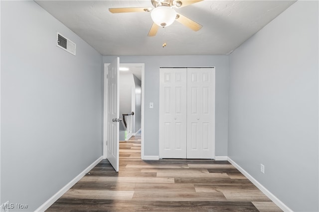 unfurnished bedroom featuring hardwood / wood-style floors, ceiling fan, a textured ceiling, and a closet