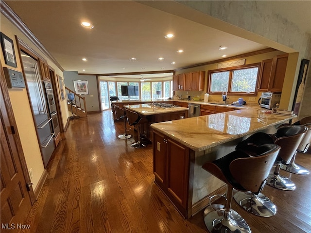 kitchen featuring a kitchen bar, kitchen peninsula, stainless steel dishwasher, dark hardwood / wood-style floors, and light stone countertops