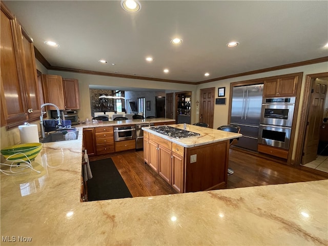 kitchen with crown molding, stainless steel appliances, a kitchen island, sink, and dark wood-type flooring