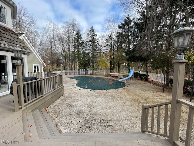 view of swimming pool with a patio area, a water slide, and a deck